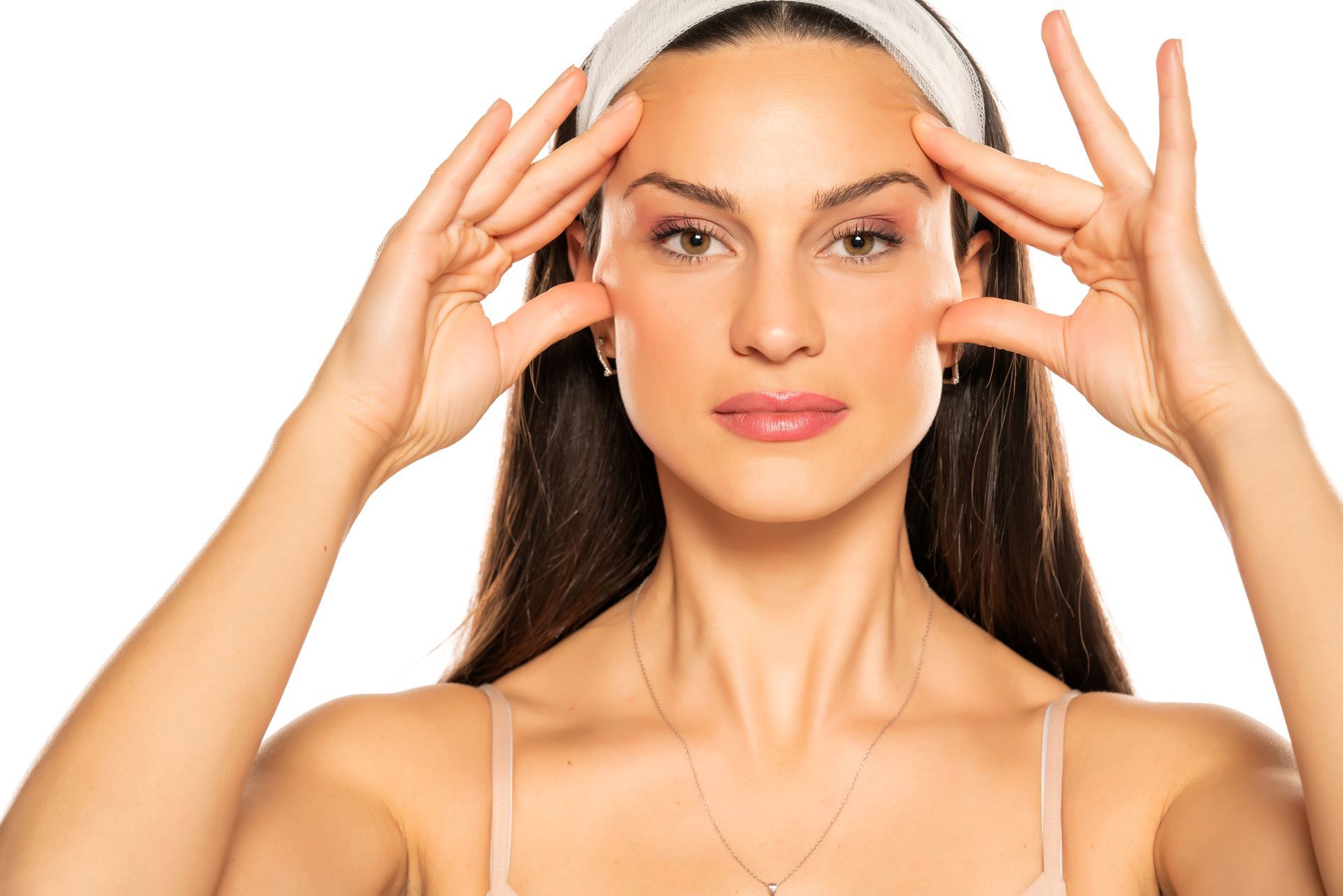 a woman is touching her face with her hands while wearing a headband .