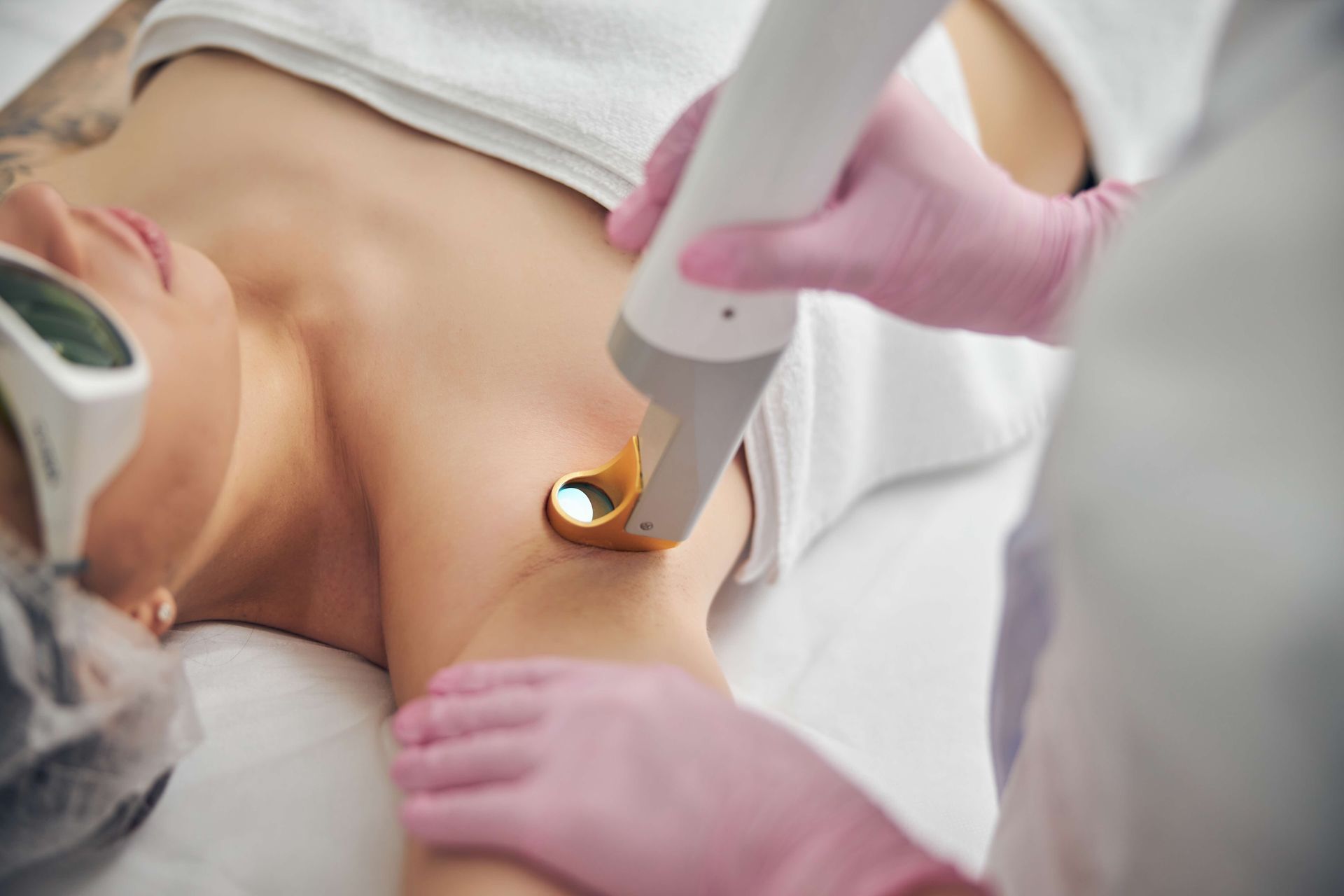 A woman is getting a laser hair removal treatment on her armpit.