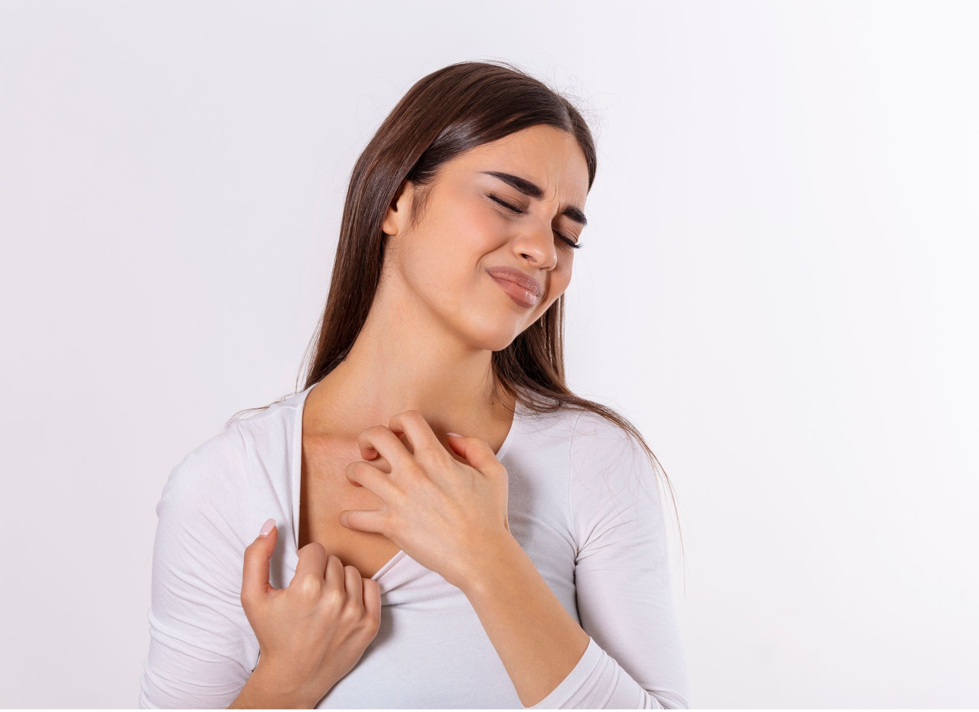 Woman scratching chest; appears uncomfortable, eyes closed. White background.