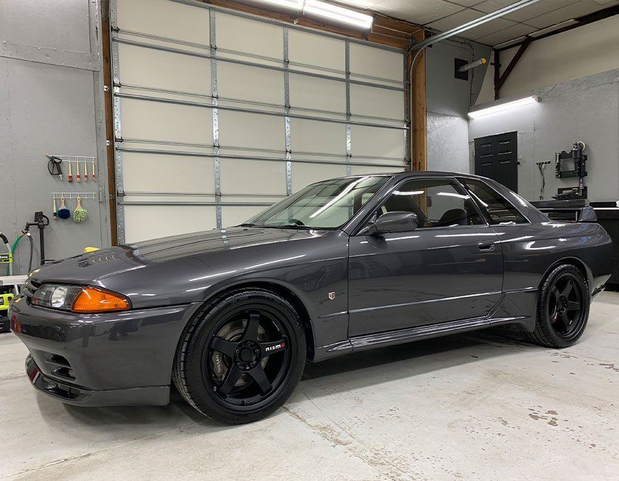 A gray car is parked in a garage next to a garage door.