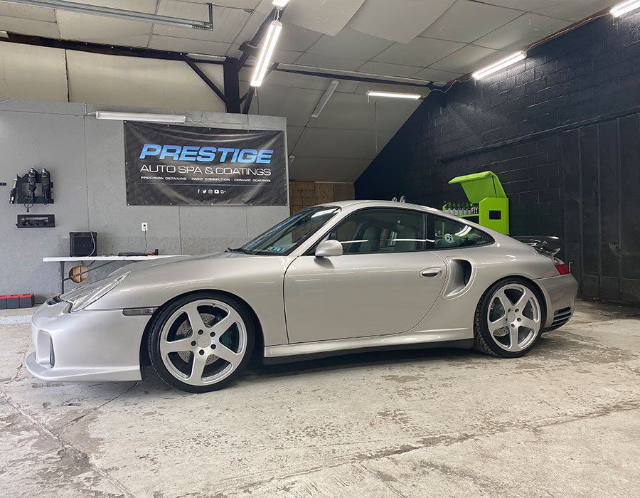 A silver porsche turbo is parked in a garage.