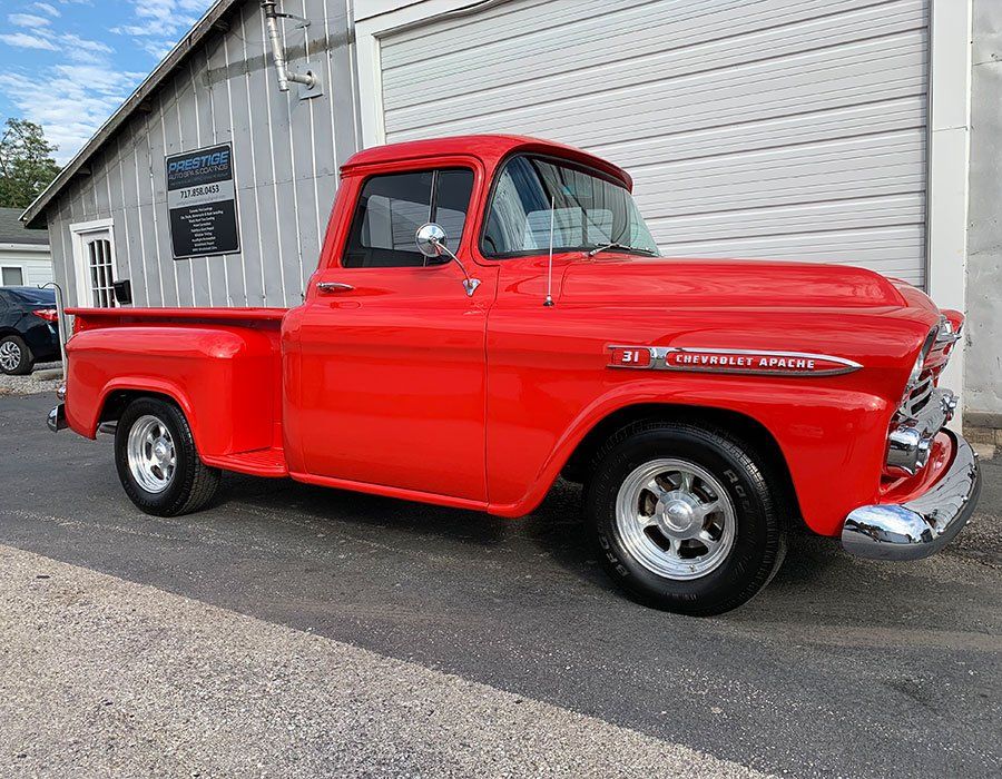 A red pickup truck is parked in front of a garage.