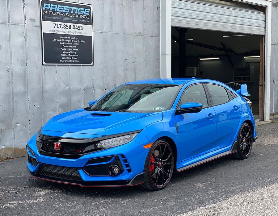 A blue honda civic type r is parked in front of a garage.
