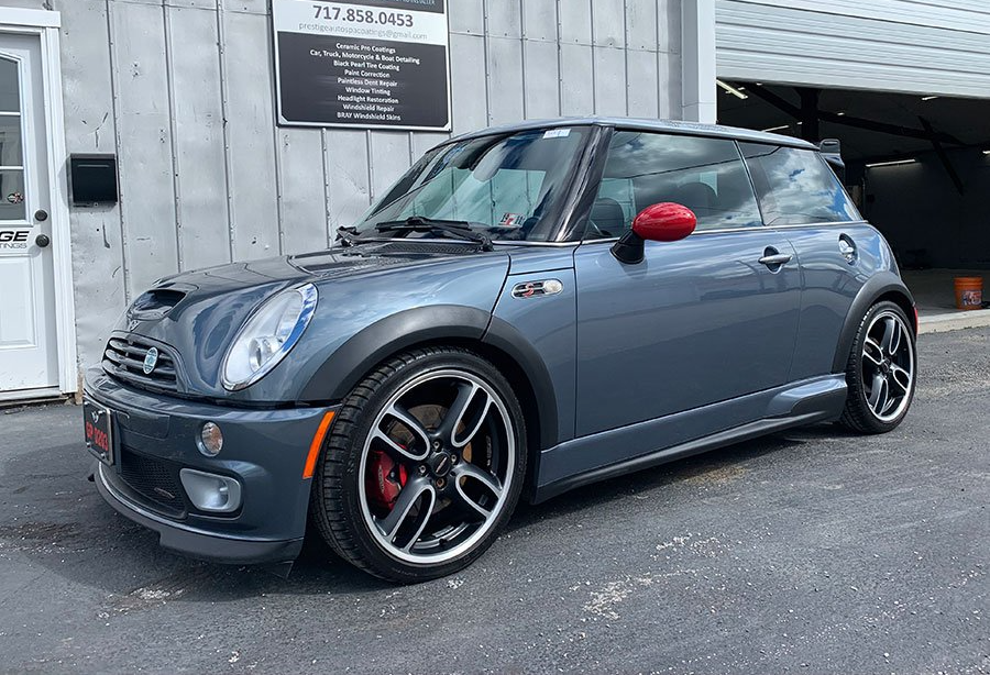 A gray mini cooper is parked in front of a garage.