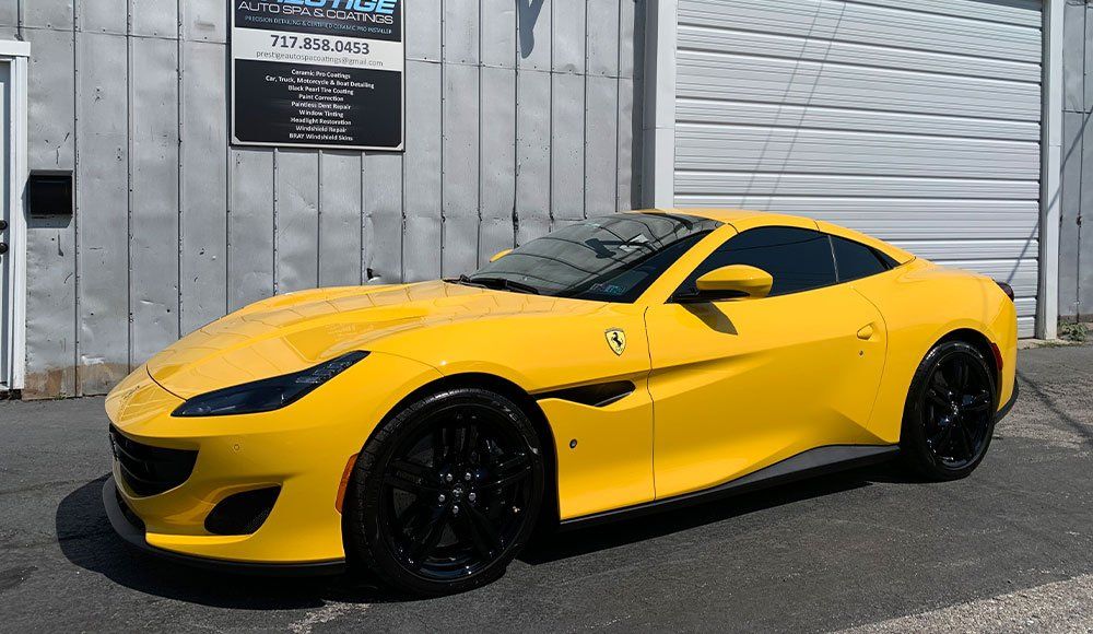 A yellow ferrari is parked in front of a garage door.