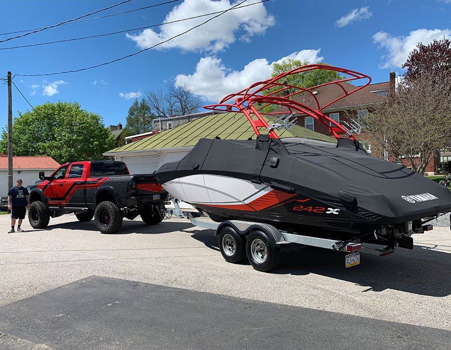 A red truck is towing a boat on a trailer.