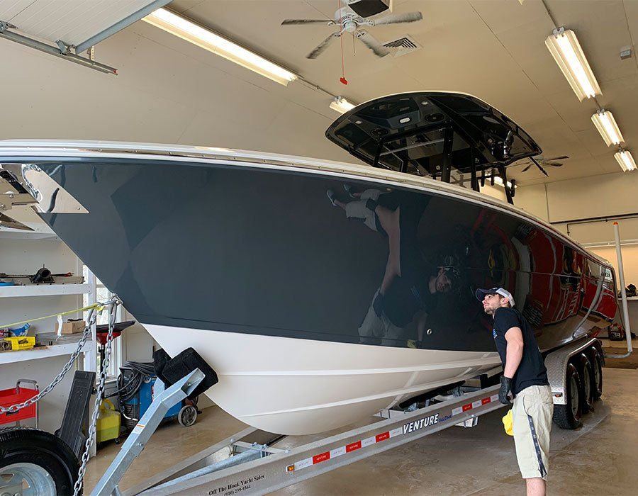 A man is standing next to a boat on a trailer in a garage.