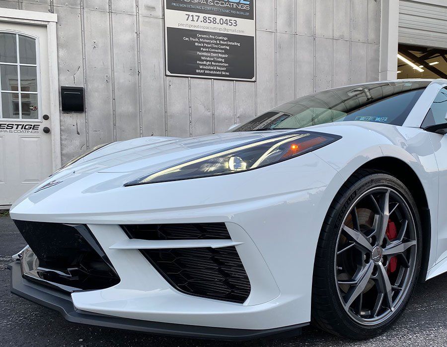 A white sports car is parked in front of a building.