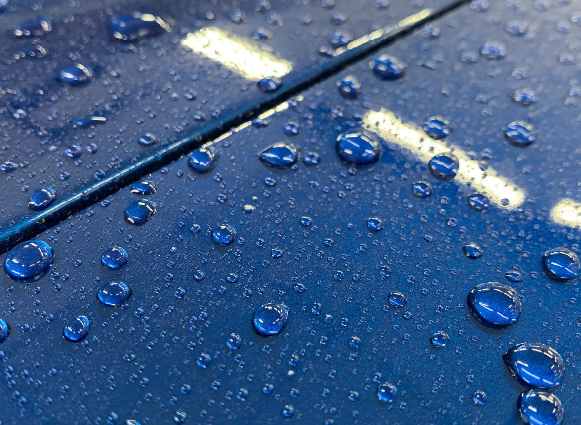 A close up of water drops on a blue surface.