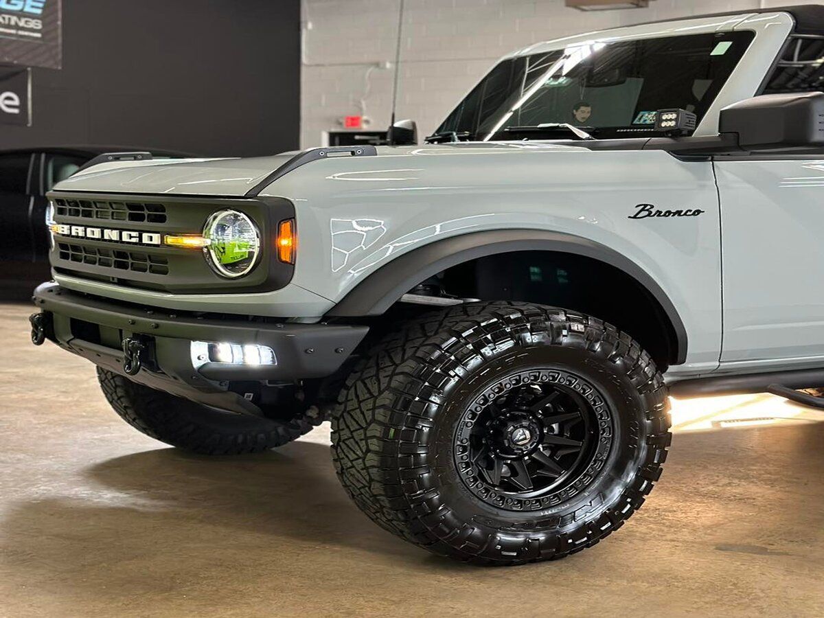 A grey ford bronco is parked in a garage.