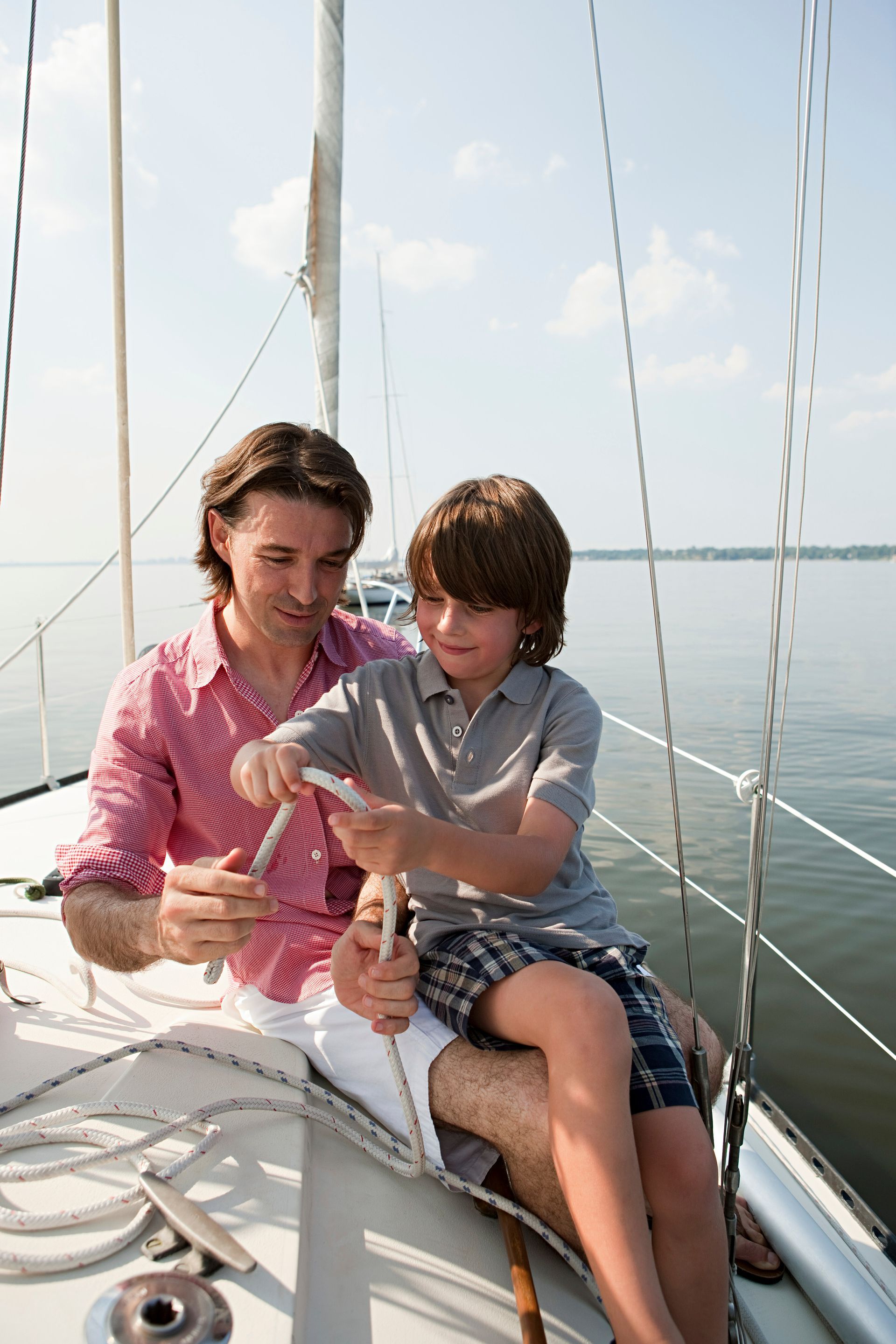 A man and a boy are sitting on a sailboat in the water.