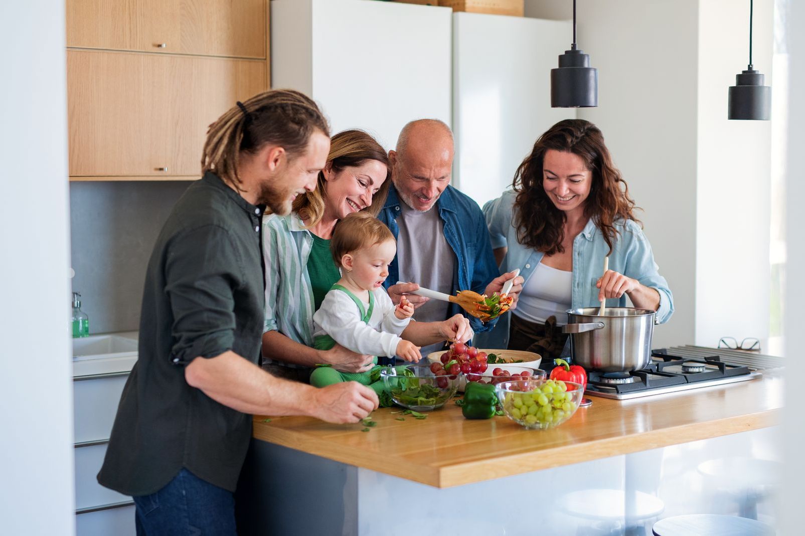 A family is preparing food together in a kitchen.