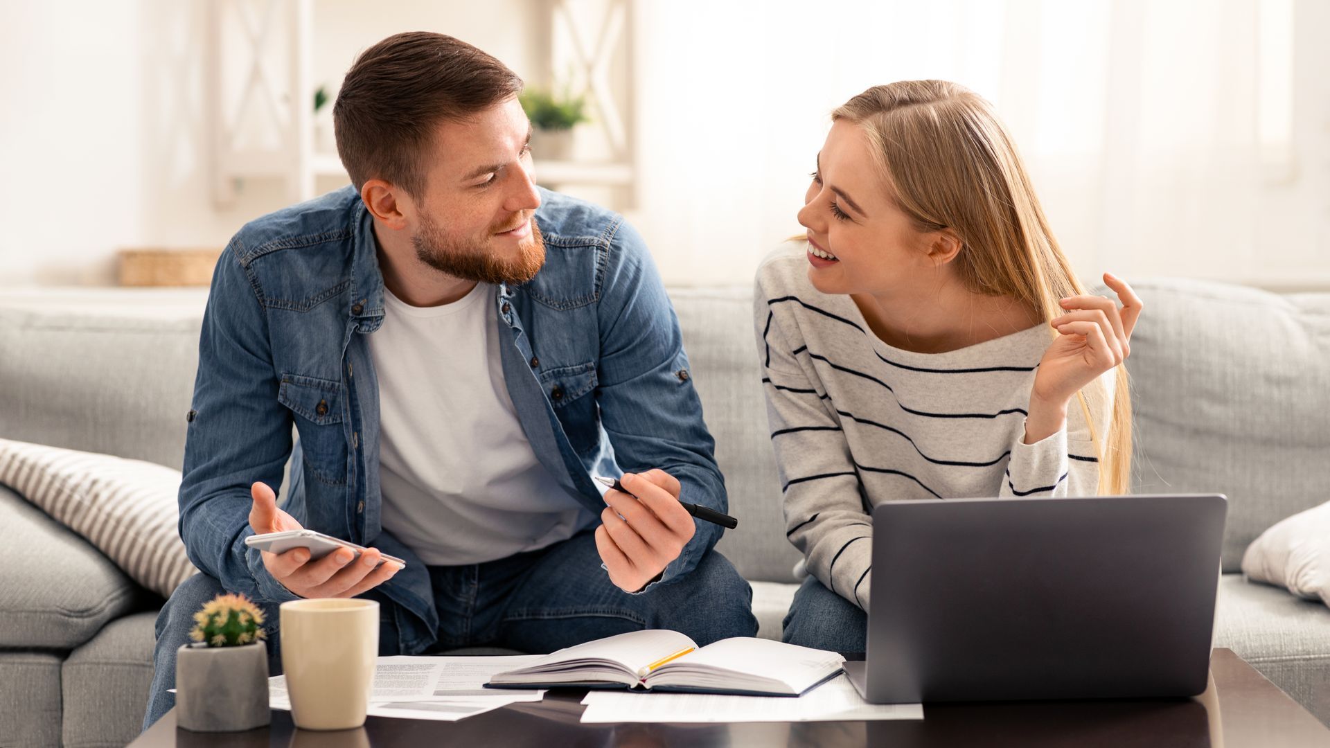 A man and a woman are sitting on a couch looking at each other.