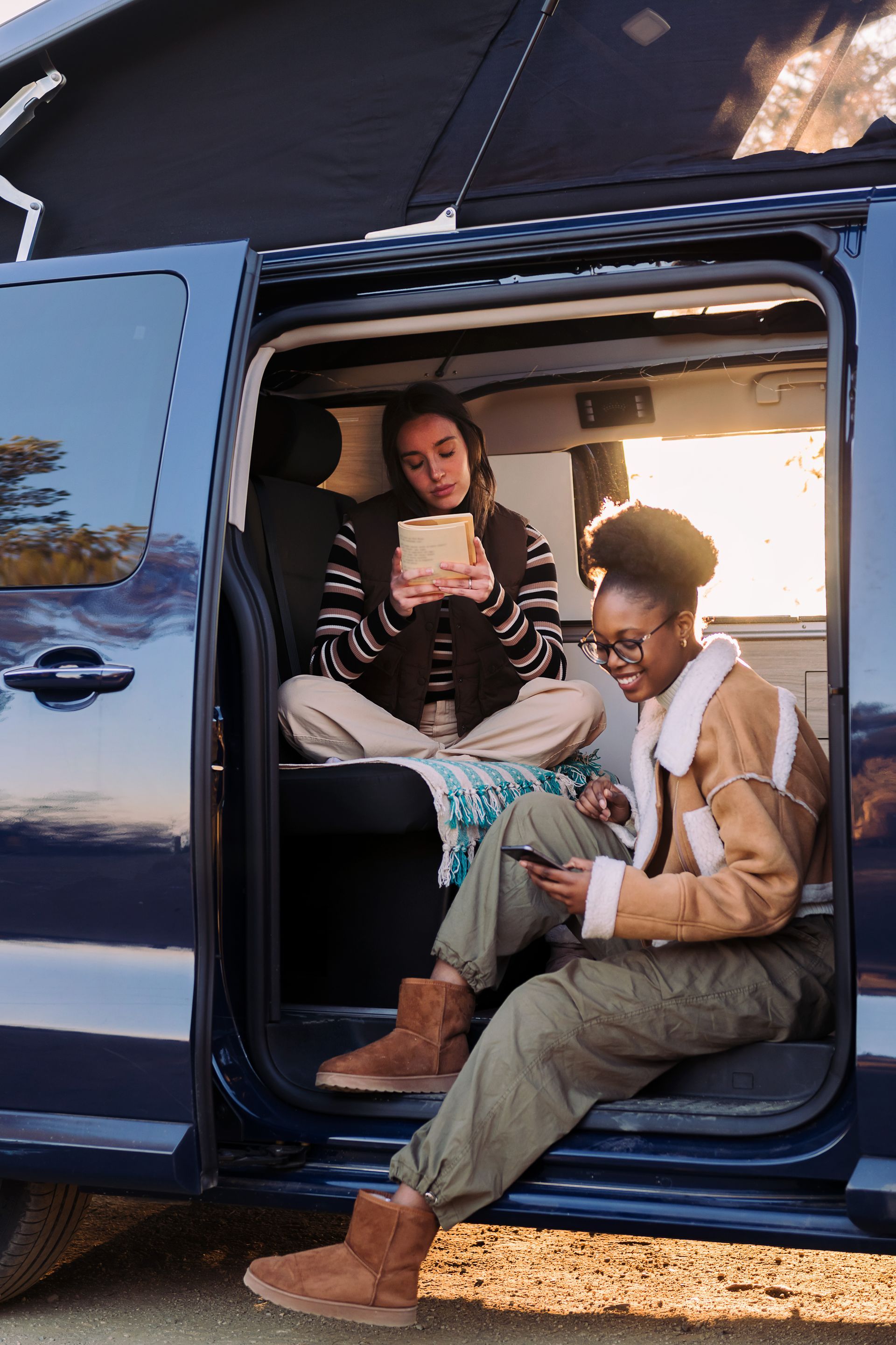 Two women are sitting in the back of a van.