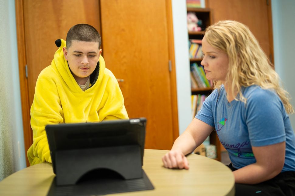 Therapist at Esperanza Children's Therapy working one-on-one with a young client using a tablet to support communication.