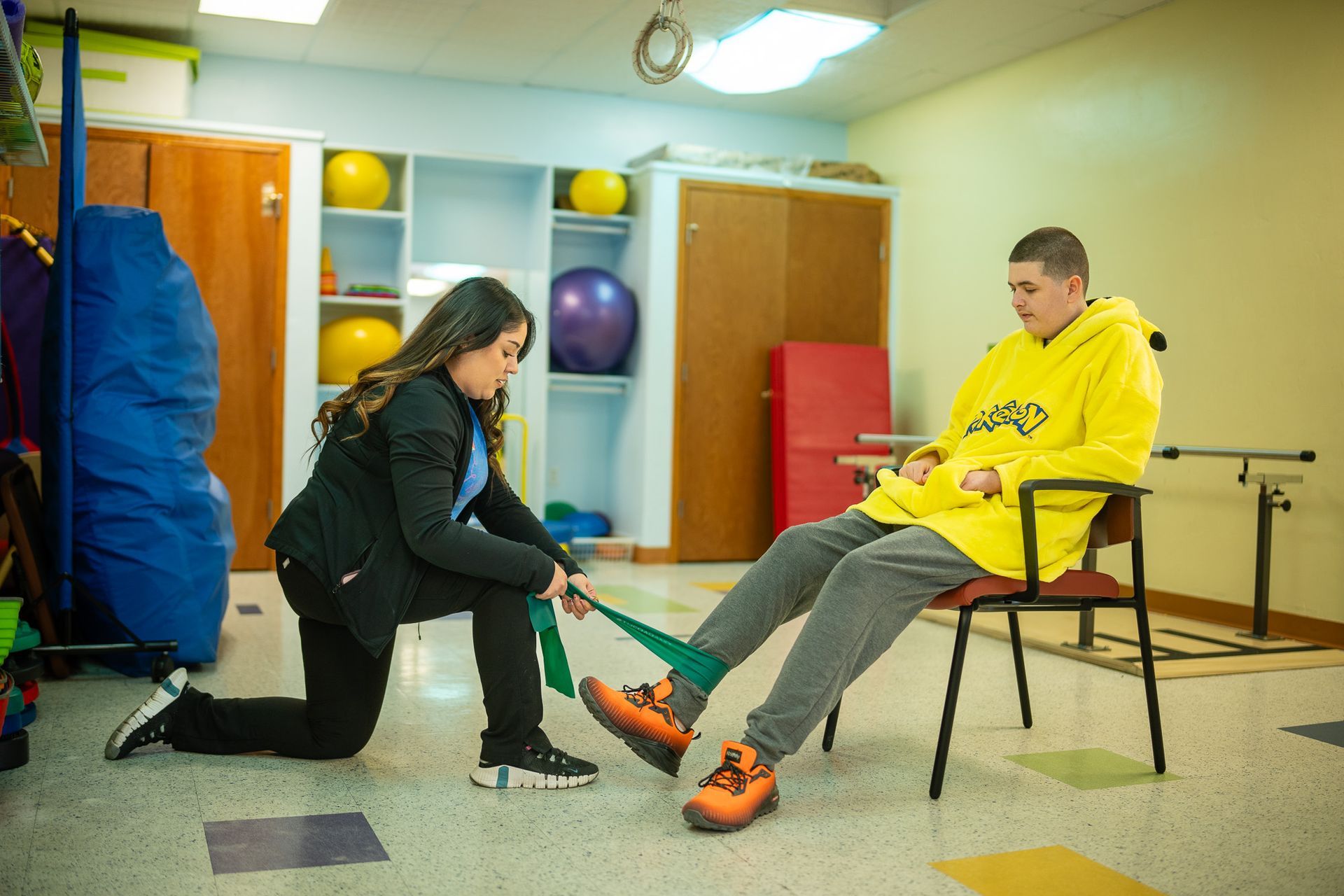 Therapist at Esperanza Children’s Therapy assisting a teenage client with resistance band exercise.