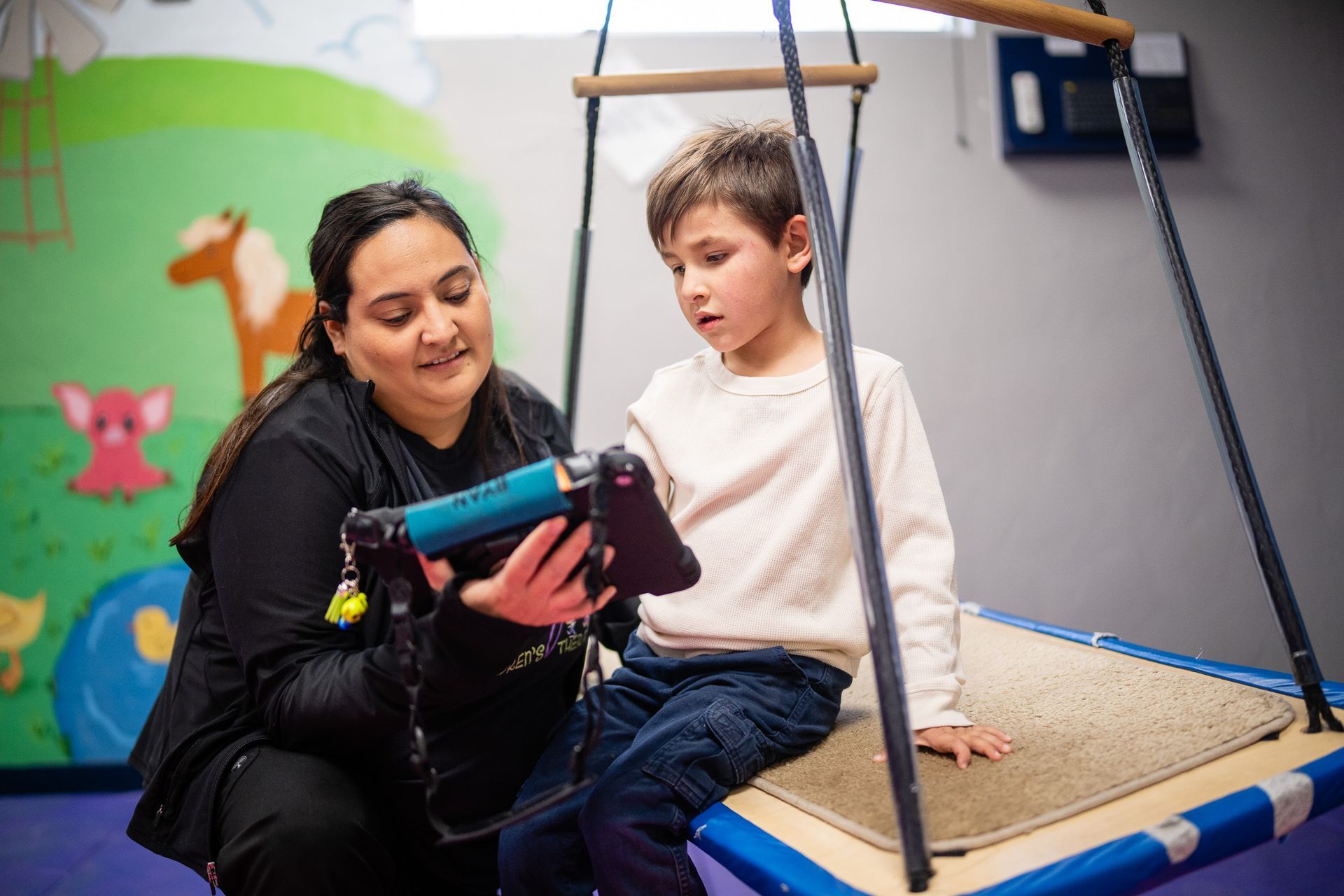 A woman is teaching a young boy how to use a tablet.