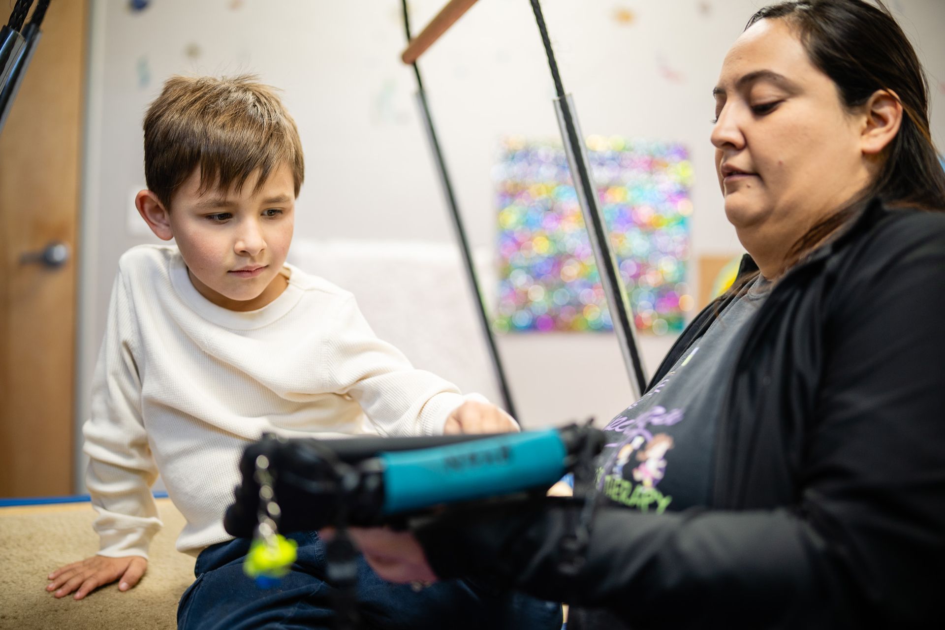 Therapist supporting a young boy with a sensory activity, reflecting Aprendamos Family of Services’ values of excellence.