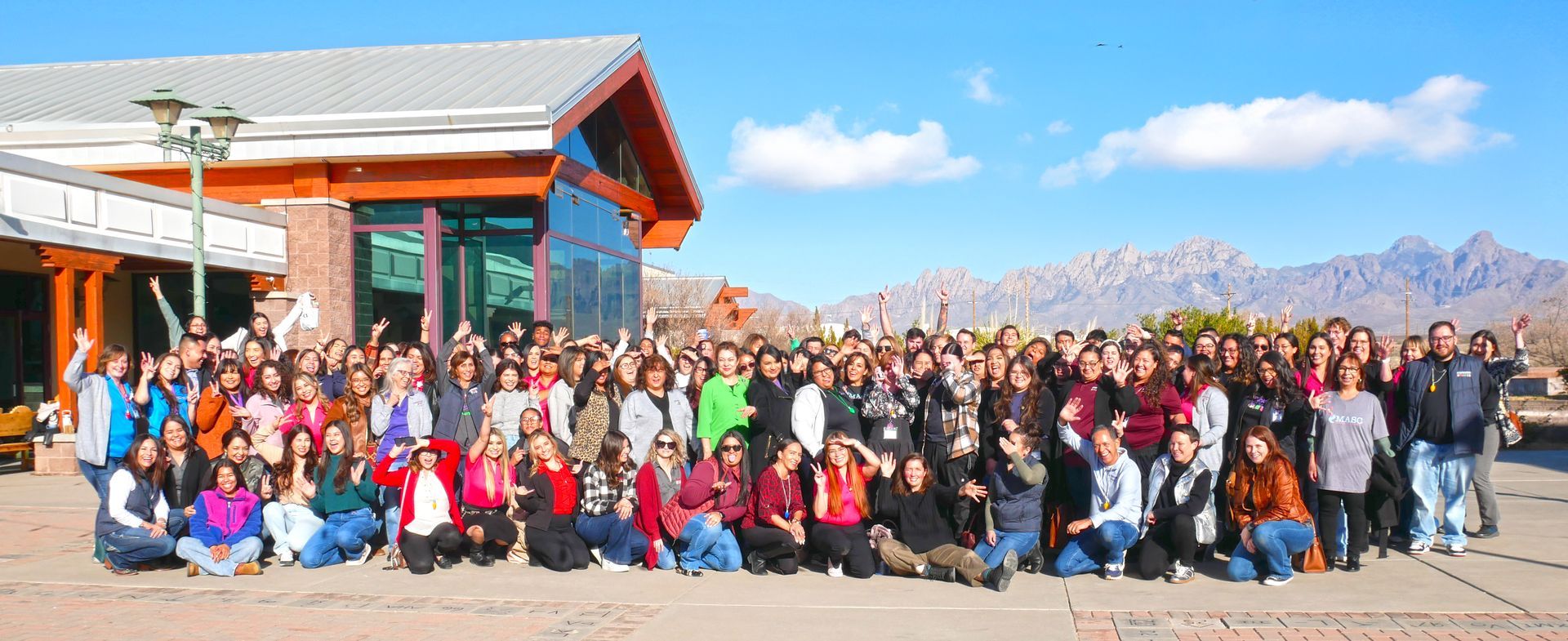 The full Aprendamos Family of Services team gathered outdoors with the Las Cruces Organ Mountains in the background.