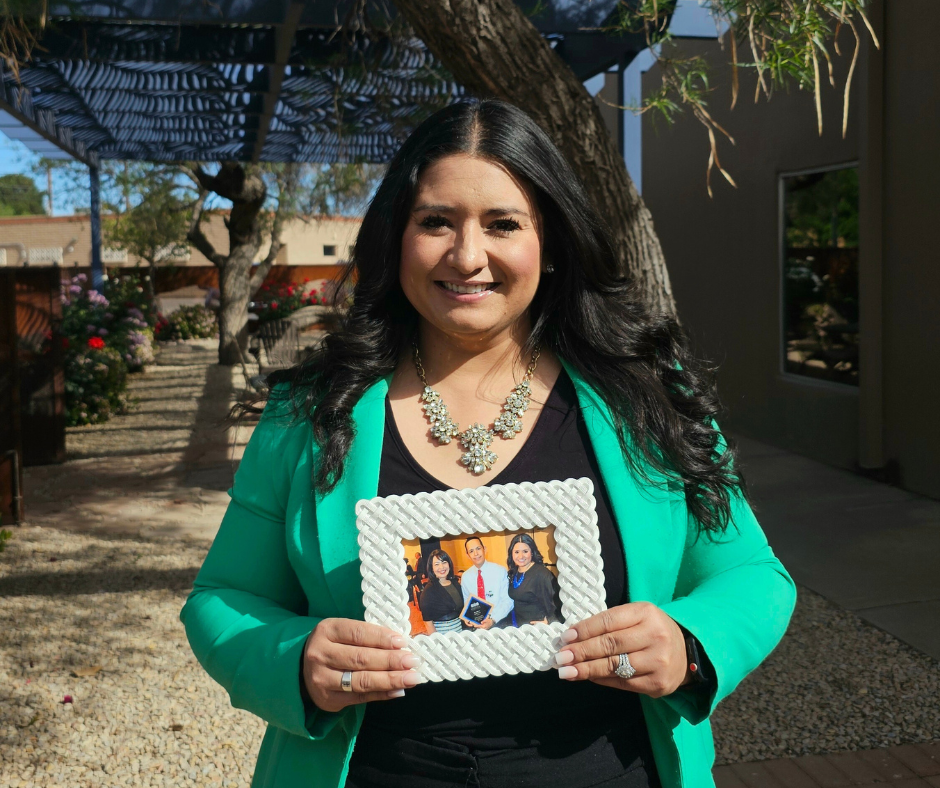 Krystal Chavarria-Gonzalez is holding a picture frame of her story at Aprendamos