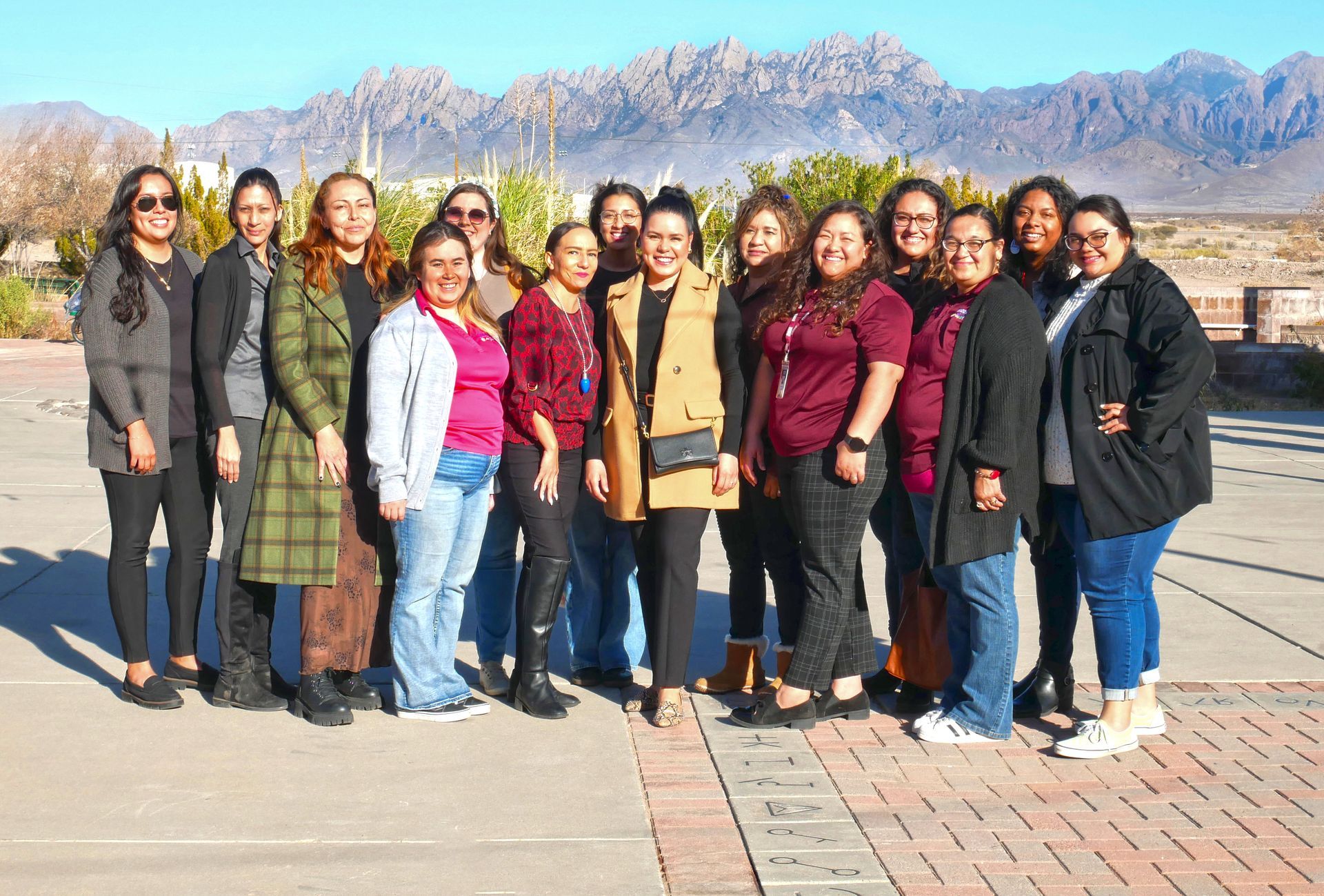 The dedicated Cariño Home Visiting team standing together outdoors in front of the Las Cruces Organ Mountains.