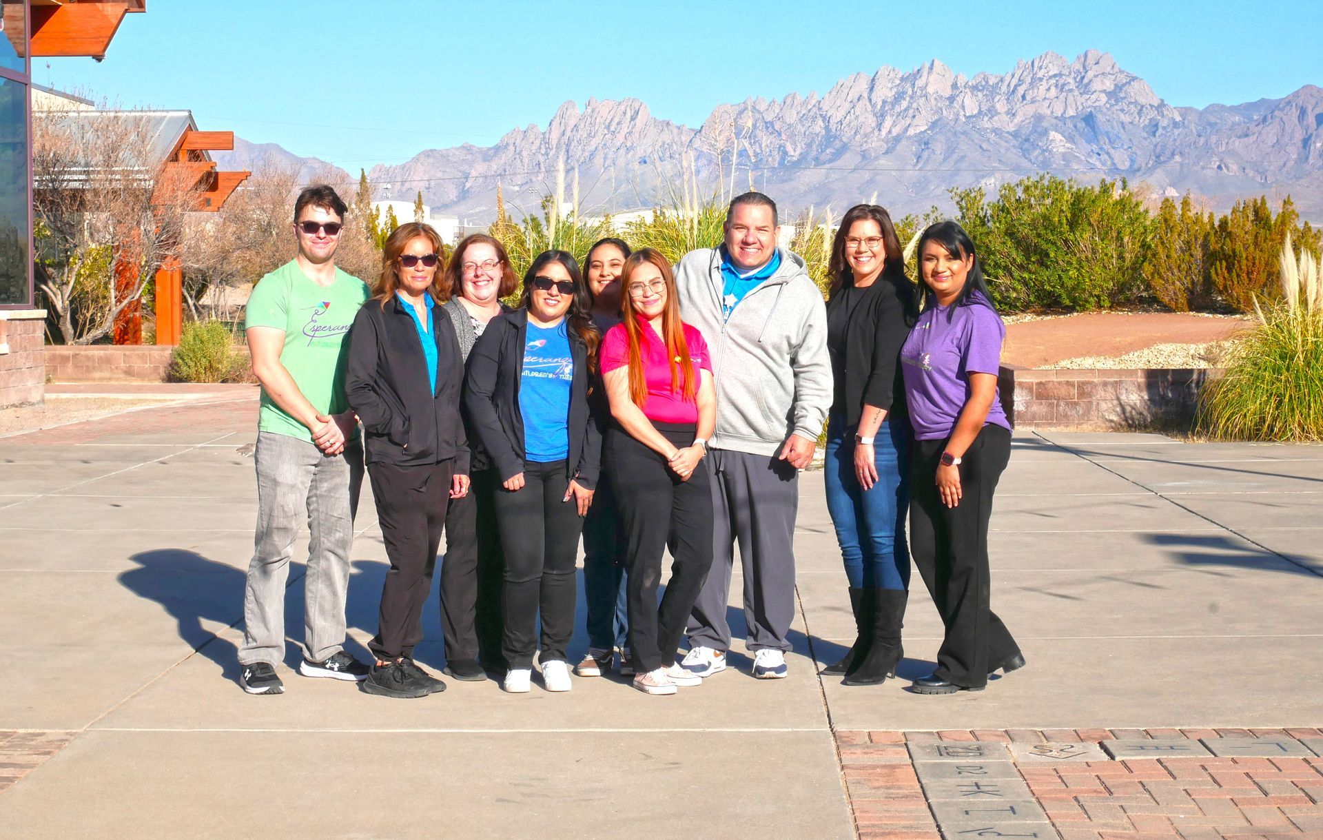 A group of women are posing for a picture with mountains in the background.