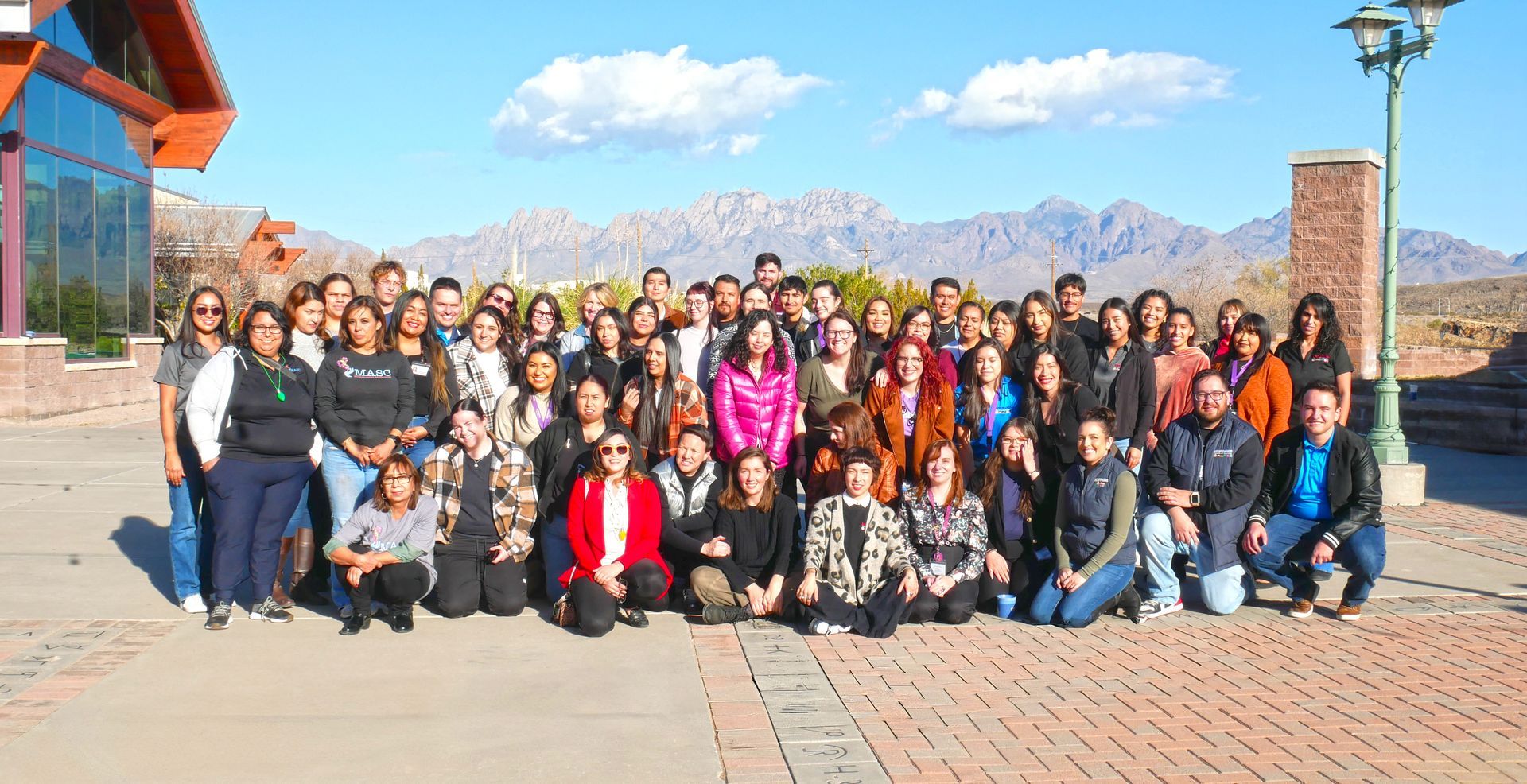 A group of women are posing for a picture with mountains in the background.