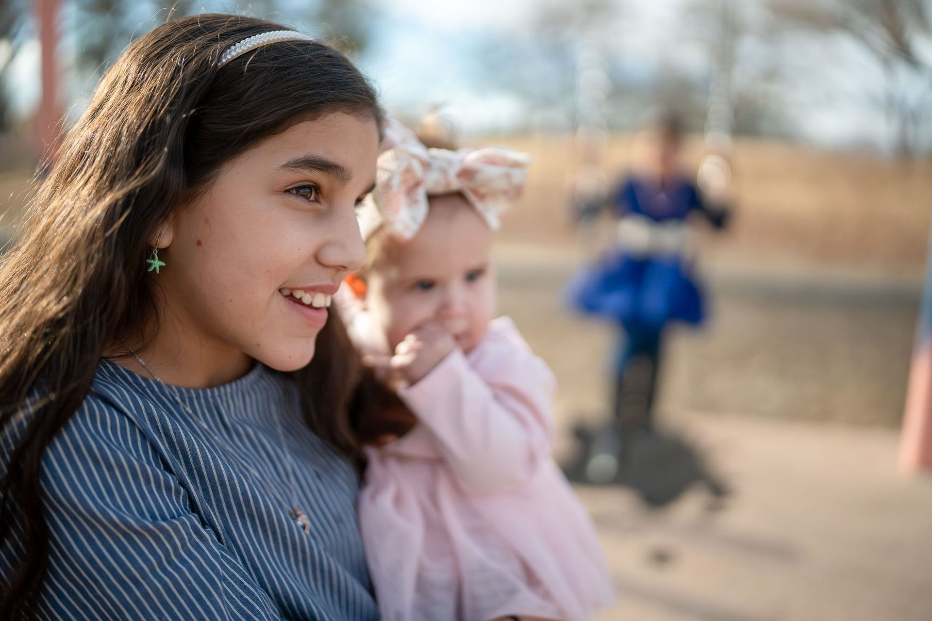 Young girl smiling while holding her baby sister Elizabeth during a Cariño Home Visiting Program outing.