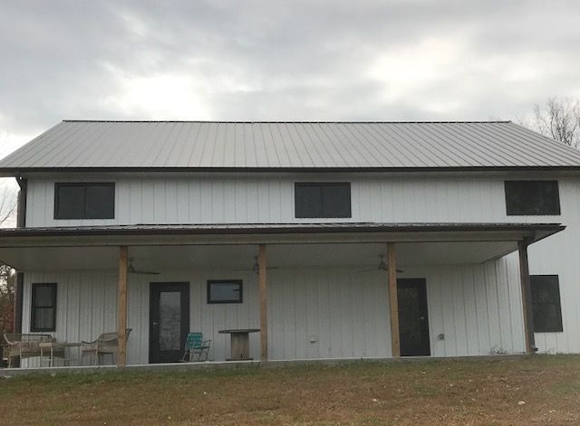 A large white house with a porch and a metal roof.
