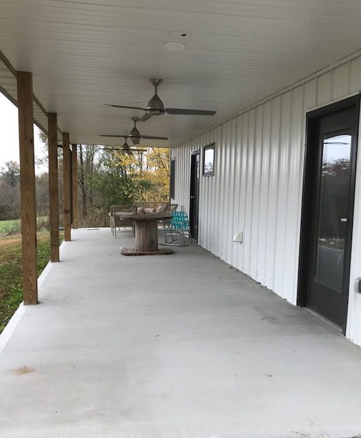 A covered porch with a table and ceiling fans