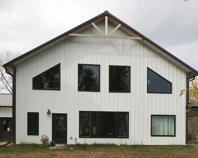 A large white house with black windows and a brown roof.