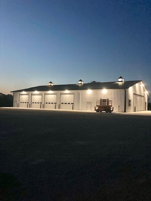 A large white building with a lot of garage doors is lit up at night.