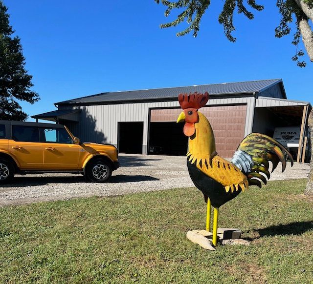 A yellow car is parked in front of a chicken statue