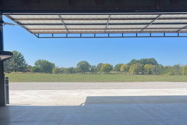 A view of a field from inside a garage door.