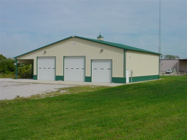 A large building with three garage doors and a green roof