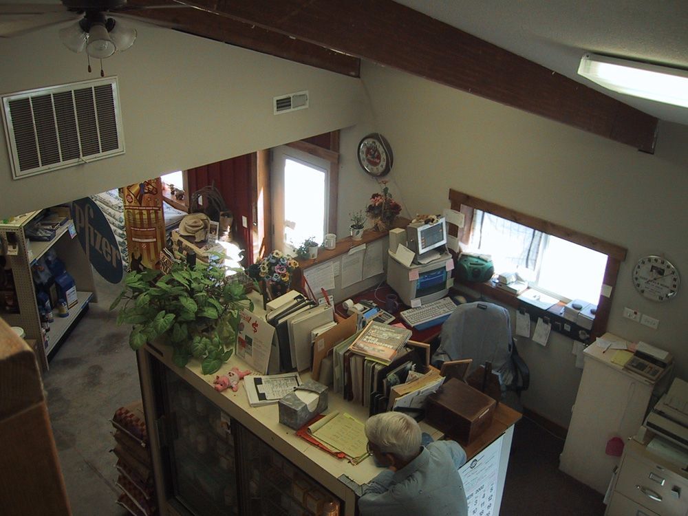A man sits at a desk in a room with a clock on the wall