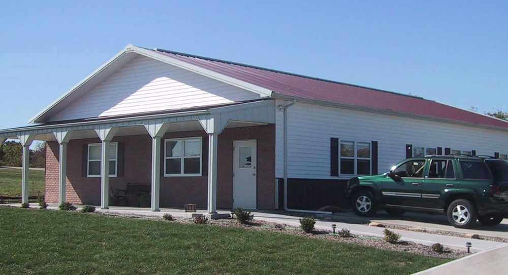 A green suv is parked in front of a house with a red roof