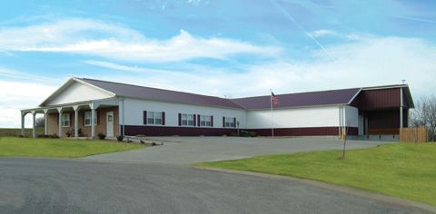 A large white building with a purple roof and a porch