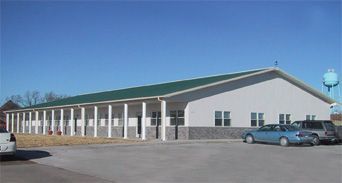 A white building with a green roof and a water tower in the background
