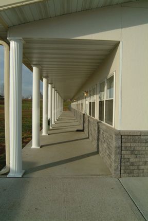 A long walkway with columns and windows on the side of a building