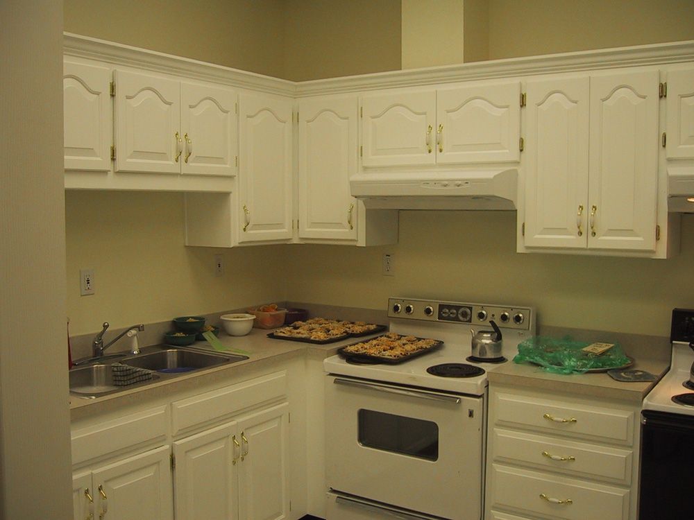 A kitchen with white cabinets , a stove and a sink