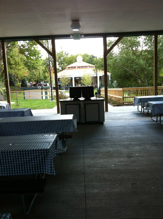 A covered area with tables and a gazebo in the background