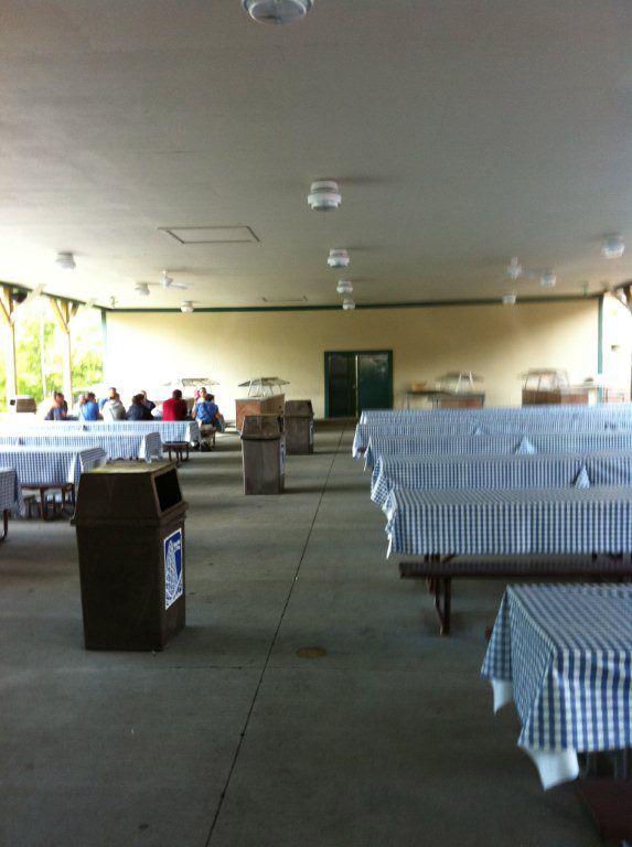 A large room with tables and benches and a trash can