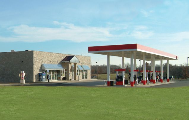 A gas station with a red canopy and a building in the background