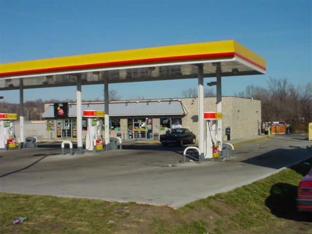 A gas station with a yellow roof and red stripes