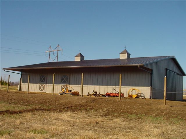 A large barn is sitting in the middle of a field