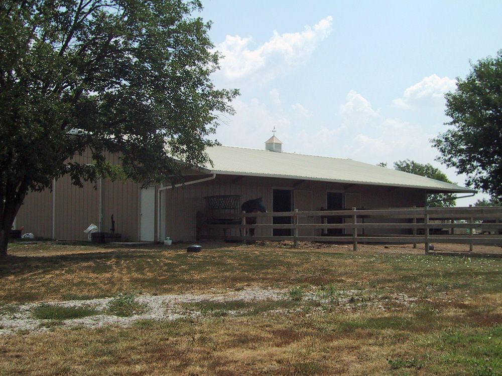 A barn with a white roof and a wooden fence around it