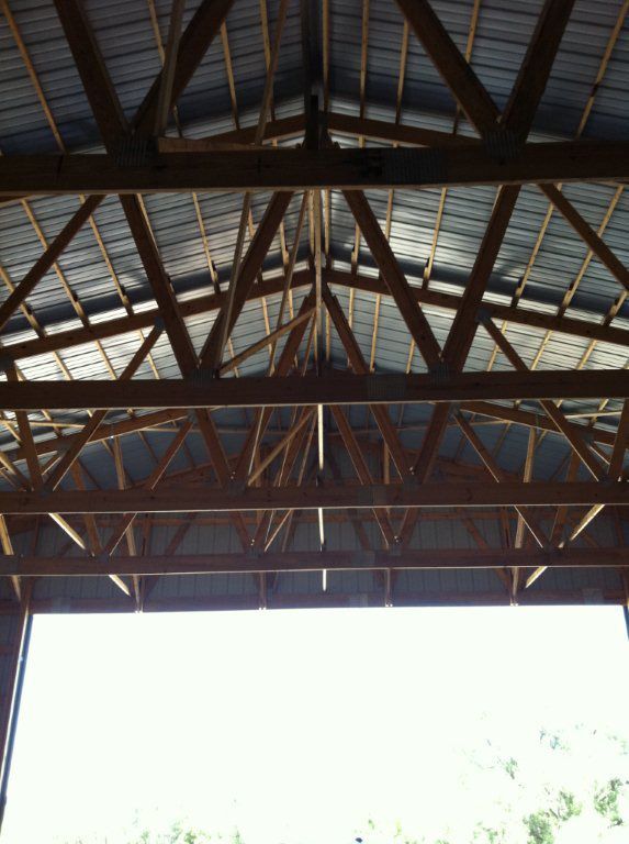 The ceiling of a building with wooden beams and a metal roof
