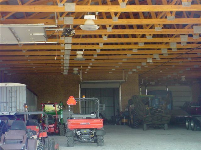A tractor is parked in a garage with other vehicles