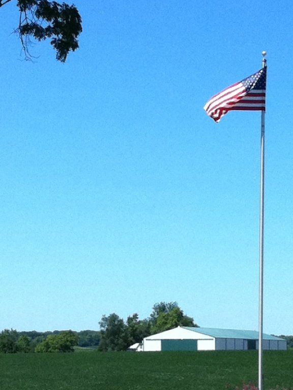 An american flag is flying in front of a barn